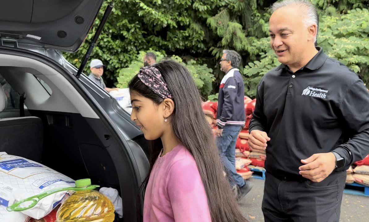 Dr. Shah and a child looking at materials in a car trunk.