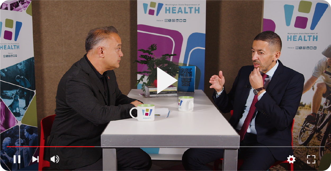 Dr. Umair Shah and Sandro Galea talking at a table.