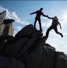 Image of someone holding another person from falling off of a ledge.