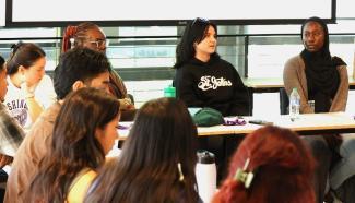 Students sit around a table and talk.